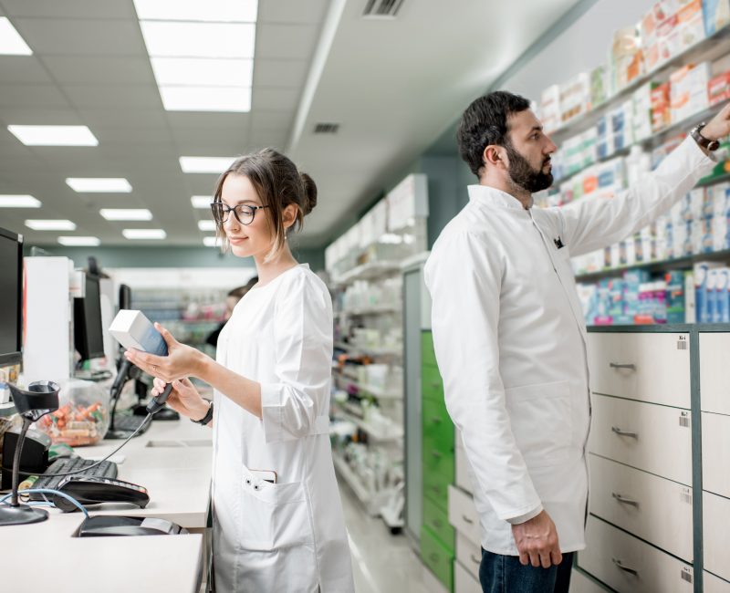 Pharmacists working in the pharmacy store Man and woman pharmacists working at the cash register of the modern pharmacy store