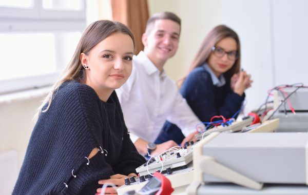 Group of young students in technical vocational training with teacher, the lesson in technical college, with young female student in front of camera. Group of young students in technical vocational training with teacher, the lesson in technical college, with young female student in front of camera.