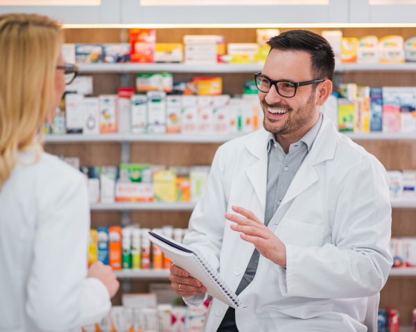 Cheerful pharmacist talking to his female colleague. Cheerful pharmacist talking to his female colleague.